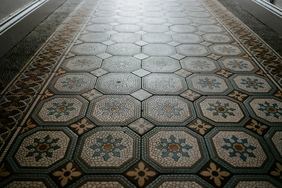 Sol ancien en carreaux de ciment à motifs géométriques, dans un couloir