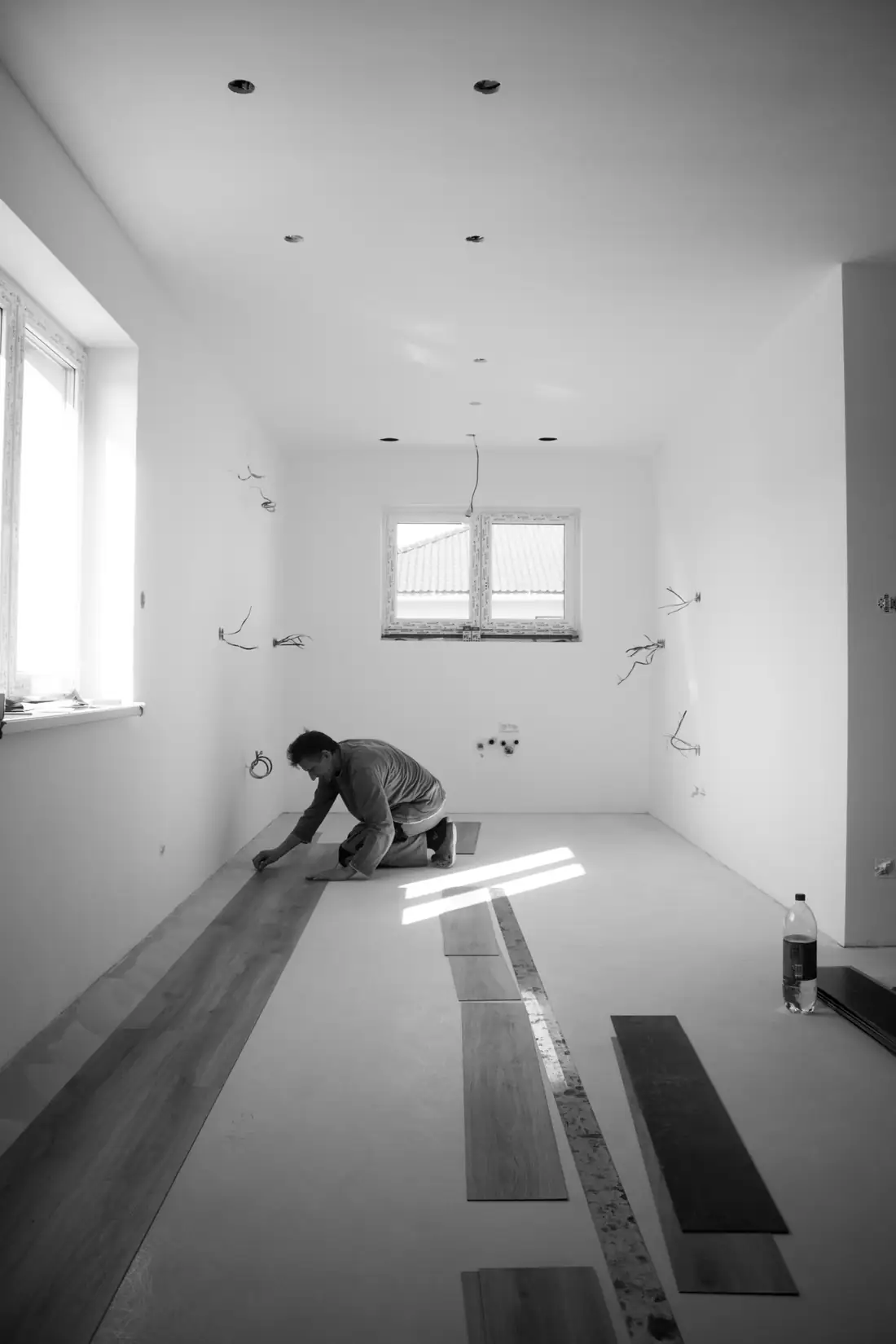 Artisan agenouillé au sol dans une pièce vide en cours de rénovation