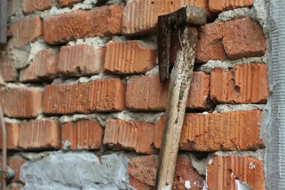 Vieille hachette plantée dans un mur de briques en démolition