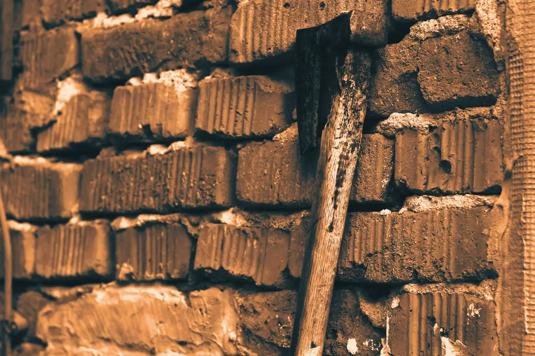 Vieille hachette plantée dans un mur de briques en démolition