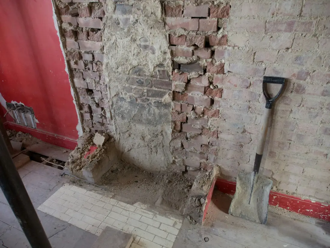 Pelle appuyée contre un mur de briques à moitié démoli